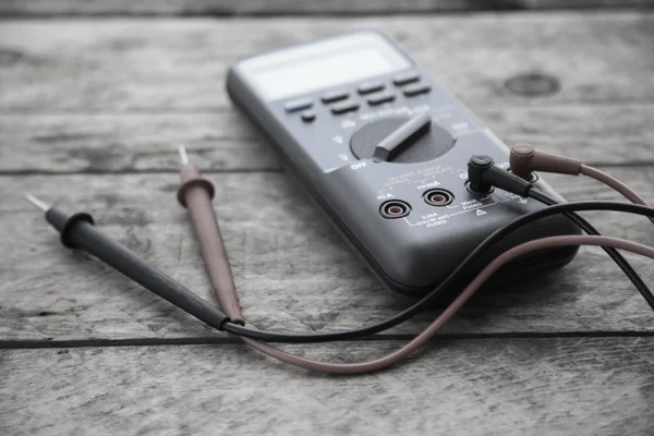 Nahaufnahme von digitalem Multimeter auf hölzernem Hintergrund, Arbeiter benutzte elektronische Werkzeuge für kontrollierte Schaltung, spezielle Werkzeuge für elektronische Arbeit. — Stockfoto