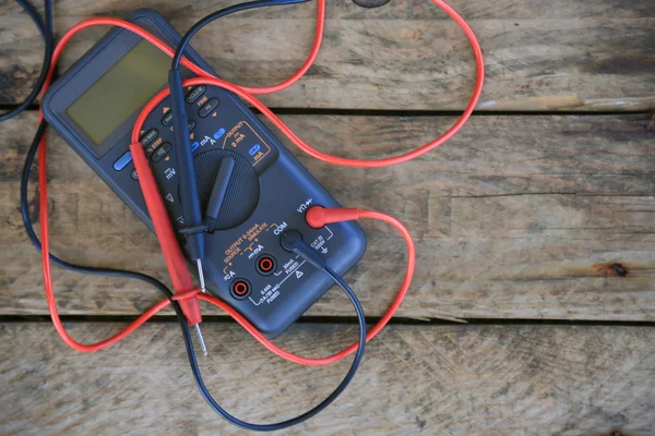 Detail digitální multimetr na dřevěné pozadí, pracovník používá elektronické nástroje pro zaškrtnutých obvodem, speciální nástroje na elektronické práce. — Stock fotografie