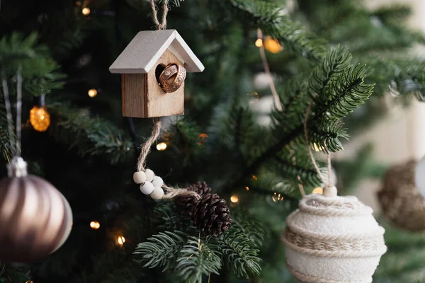 Christmas toys house and wedding rings on the branches of Christmas tree decorated for the celebration of Christmas and New Year