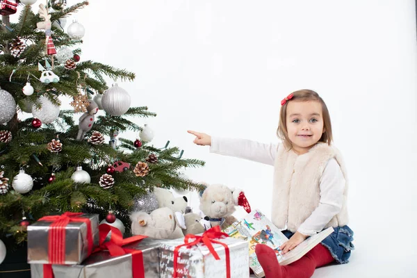 Smiley toddler girl pointing towards Christmas tree — Stock Photo, Image