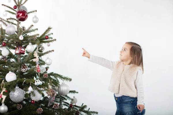 A toddler girl pointing towards the tip of the Christmas tree — Stock Photo, Image