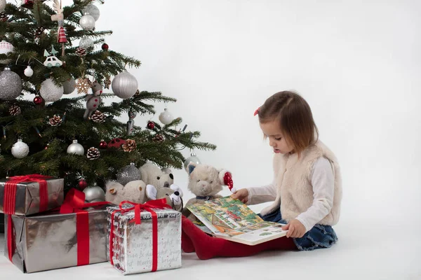Dziewczynka czytająca książkę świąteczną przyjaciołom z fsoft toys — Zdjęcie stockowe