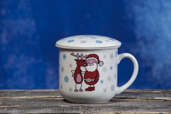 Christmas cup with reindeer, Santa and snowflakes on a blue background — Stock Photo, Image