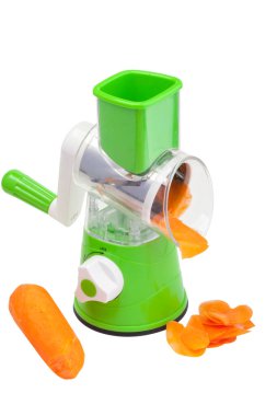 Çeşitli eklentileri olan sebze kesicisi. Masanın üzerinde duruyor. Beyaz bir arkaplanda.