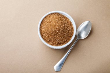 Kahverengi arka planda porselen beyaz kase esmer şeker. Çubuk şeker