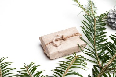 Hediye kutusu, çam kozalakları ve beyaz arka planda köknar dalları olan Noel sınırı. Yukarıdan görüntüle.