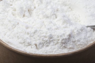 Siyah bir masanın üzerinde bir kasede hindistan cevizi unu. Yukarıdan görüntüle