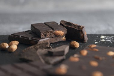 Gri arka planda fındıklı çiğ siyah çikolata.