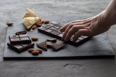 Gri arka planda fındıklı çiğ siyah çikolata.