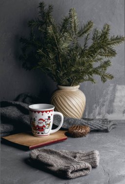 Geyik resmi olan beyaz bardak, köknar dalları arasında gri bir arka planda Noel Baba.
