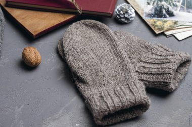 Gri örgü eldivenler yeni yıl kartları ve kitaplarının yanında masanın üzerinde yatar. Kendi kendini yaptı. Önplan.