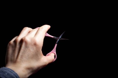 Koyu arkaplanda izole edilmiş pembe makasları tutan yakın plan fotoğraf.