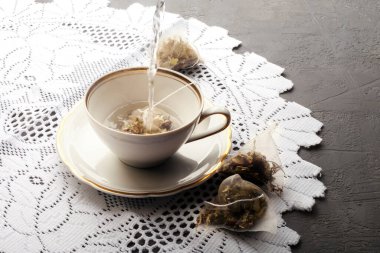 Çay piramidinin içinde beyaz fincanlı meyve çayı. Mermer arka planda kırmızı böğürtlen ve kupa. Sıcak kış havası, üst manzara