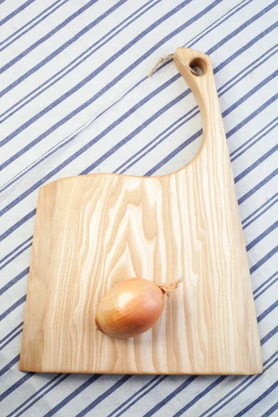 Wooden cutting board and canvas napkin on a wooden table. View from above