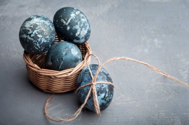 Mutlu Paskalya kartları: mermer taş efektli yumurtalar serisi, gri beton zemin üzerinde boyanmış doğal boya amber çiçeği ve metin için boş alan; üst görünüm, düz yatay