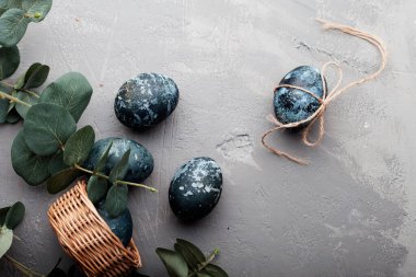 Mutlu Paskalya kartları: mermer taş efektli yumurtalar serisi, gri beton zemin üzerinde boyanmış doğal boya amber çiçeği ve metin için boş alan; üst görünüm, düz yatay