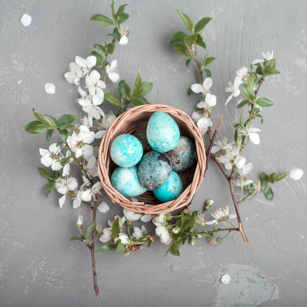 Easter colored eggs in a nest made of hay on a blue background. Seasonality concept, spring, postcard, holiday. Flat lay, copy space, space for text. Close-up.