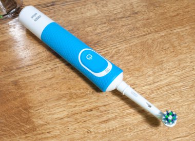 KIEV, UKRAINE - Mayıs 09, 2021: Elektrikli diş fırçası Oral-B Vitality hassas ahşap arka plan banyoda. Oral-B ağız temizliği ürünleri için bir marka adıdır..