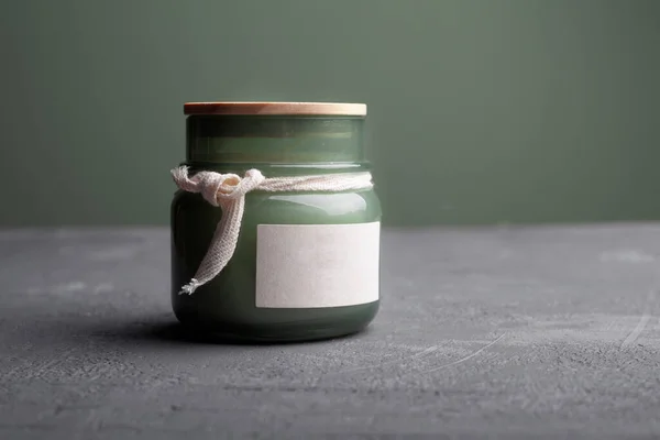 在玻璃瓶里放着芬芳的蜡烛 背景是牛皮纸 绿叶和松果 浅文背景 — 图库照片