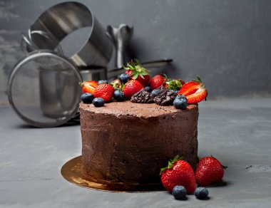 Gri arka planda böğürtlenli taze ev yapımı çikolatalı kek.