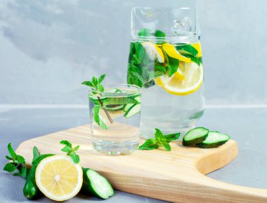 Soğuk yaz limonatası, salatalık ve taş kavanozlarda naneli taş, taş ya da beton arka plan..