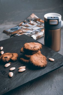 Şekersiz çiğ badem unundan, glüten ve süt ürünlerinden yapılan ev yapımı kurabiyeler termo bardağın yanındaki siyah bir taş masada.