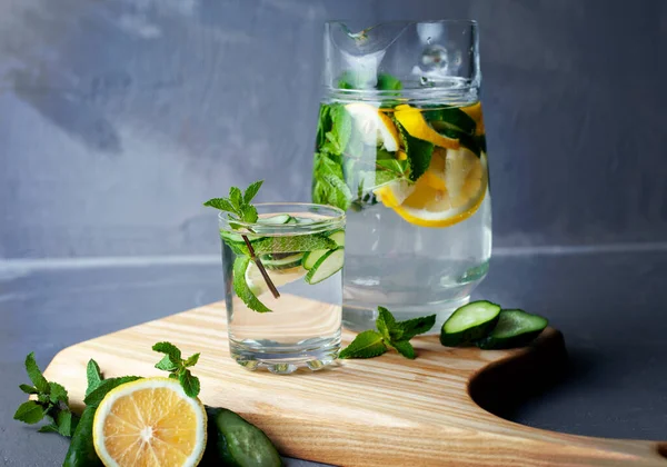 Health care, fitness, healthy food concept. Fresh cool mint lemon cucumber pour water, cocktail, detox drink, lemonade in a glass jug.