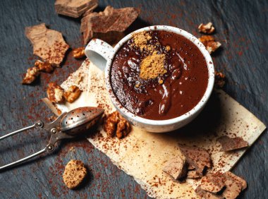 Bir fincan sıcak çikolata ve koyu beton arka planda çikolata.