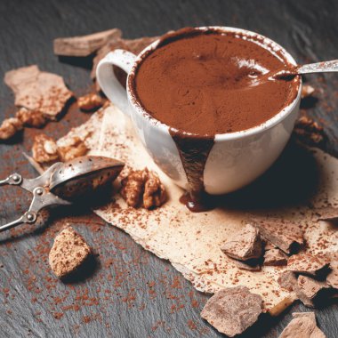 Bir fincan sıcak çikolata ve koyu beton arka planda çikolata.