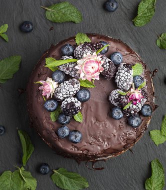 Taze nefis ev yapımı çikolatalı pasta, üstünde böğürtlen olan siyah masa, üst manzara.