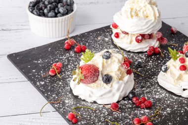 Anna Pavlova pastası üzümlü, yaban mersinli ve çilekli. Siyah mermer bir tabakta