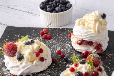 Anna Pavlova pastası üzümlü, yaban mersinli ve çilekli. Siyah mermer bir tabakta