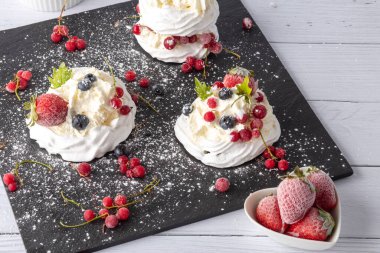 Anna Pavlova pastası üzümlü, yaban mersinli ve çilekli. Siyah mermer bir tabakta