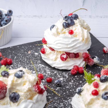 Anna Pavlova pastası üzümlü, yaban mersinli ve çilekli. Siyah mermer bir tabakta