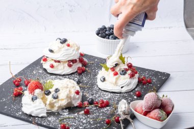 Anna Pavlova pastası üzümlü, yaban mersinli ve çilekli. Siyah mermer bir tabakta