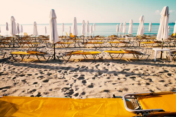 Şemsiye ve şezlonglar denizin kenarında