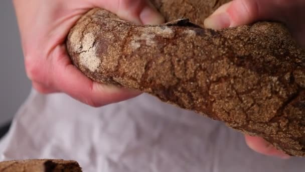 Le mani spezzano il pane. Carboidrati nocivi. Il fornaio strappa il pane fresco primo piano — Video Stock