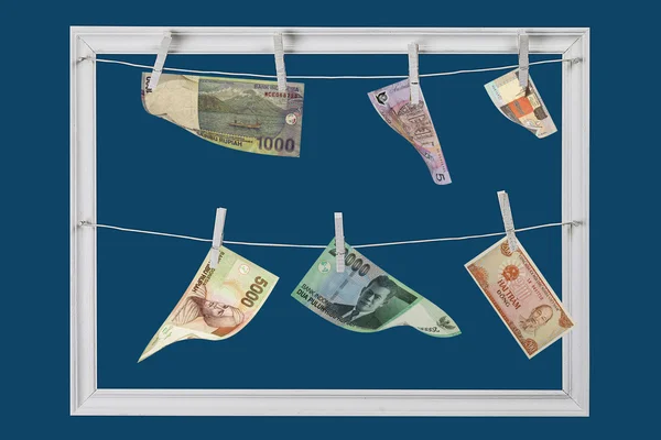 Weißer Holzrahmen, der an Wäscheklammern hängt, Banknoten aus verschiedenen Ländern — Stockfoto