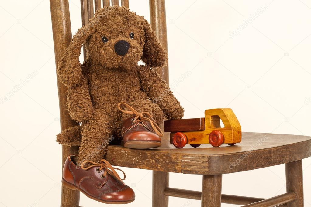 Cute Soft toy puppy sitting on a chair in old leather shoes