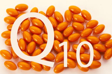 Coenzyme Q10. The inscription on the background of orange capsules clipart