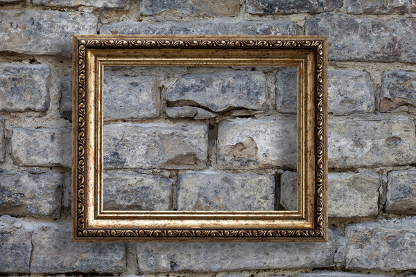 Empty golden frame on a brick wall background