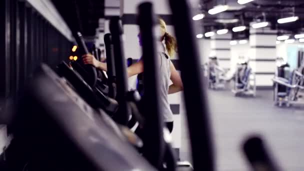 Vue de salle de gym emty avec une fille sur entraîneur elliptique — Video