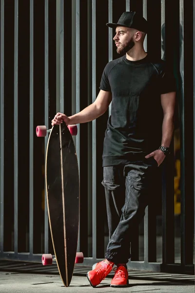 Longboard tutarak ve poz sakallı hippi adam