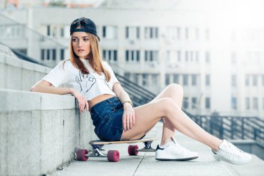 Kentsel peyzaj longboard üzerinde oturan genç kadın