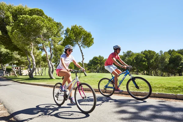 Ориуэла, Испания - 17 июня 2016 года: Пара велосипедистов, мальчик и девочка, собирается возле красивых полей для гольфа на велосипедах — стоковое фото