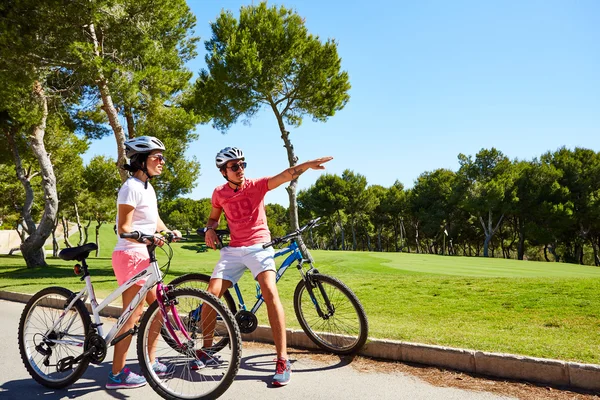 Ориуэла, Испания - 17 июня 2016 года: Пара велосипедистов, мальчик и девочка, собирается возле красивых полей для гольфа на велосипедах — стоковое фото