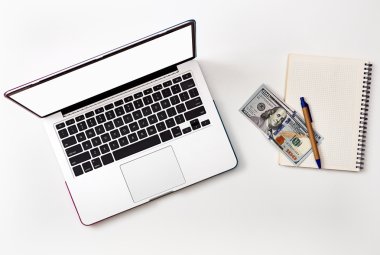 Dizüstü ekran ve para üstünde beyaz defter alay