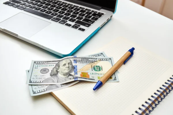 Contant geld liggen op de notebook naast een laptop — Stockfoto