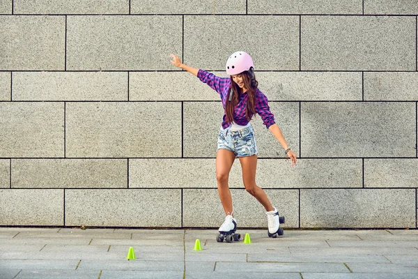 Menina bonita em um capacete aprende a andar de patins segurando equilíbrio — Fotografia de Stock