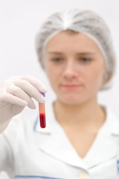 Doctor in de uniforme kijken op de test-buis met bloed — Stockfoto